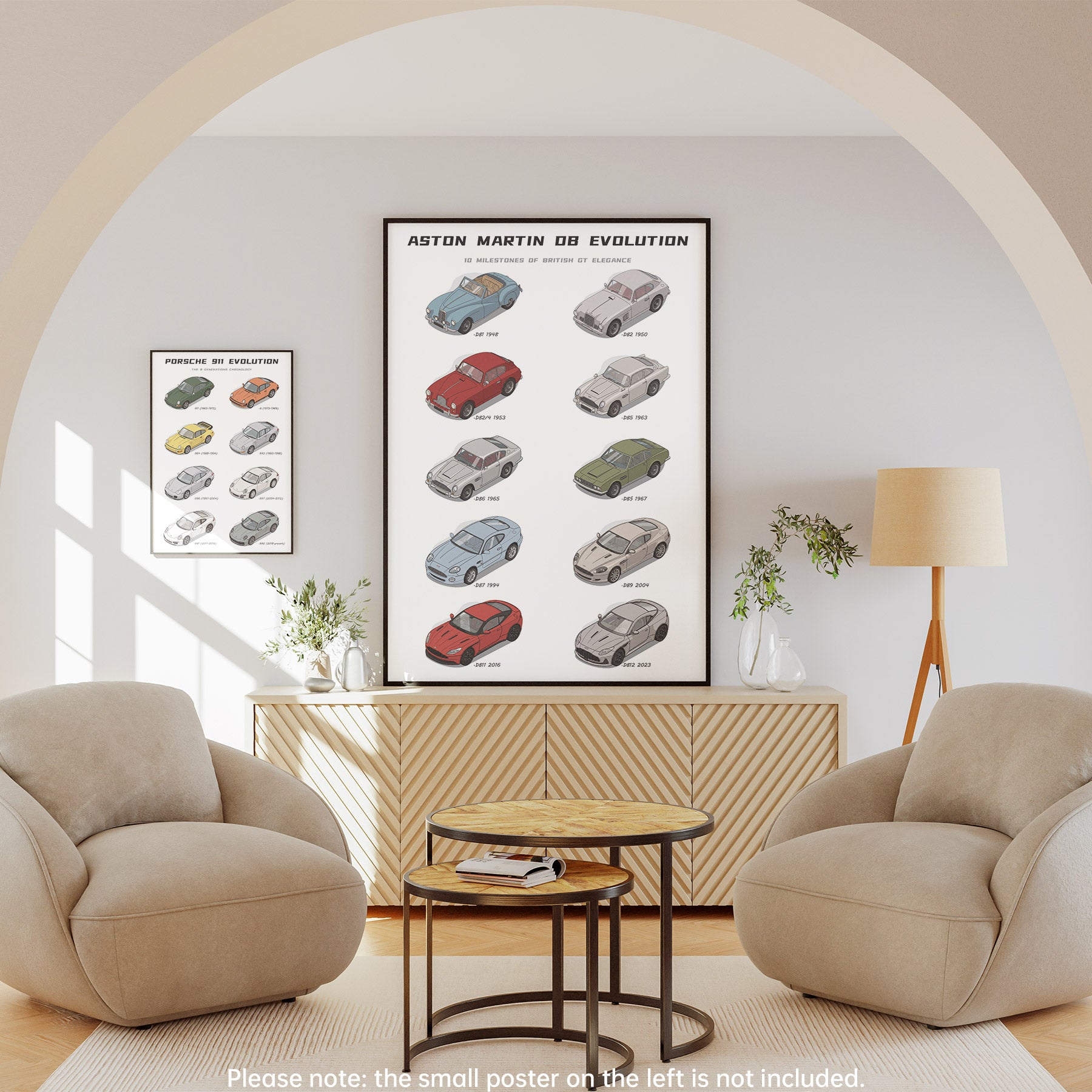A framed vertical car poster reading 'ASTON MARTIN DB EVOLUTION' hangs on a light gray wall in a styled living room with two beige armchairs, a wood cabinet, a floor lamp, and a small matching side poster partially visible to the left.