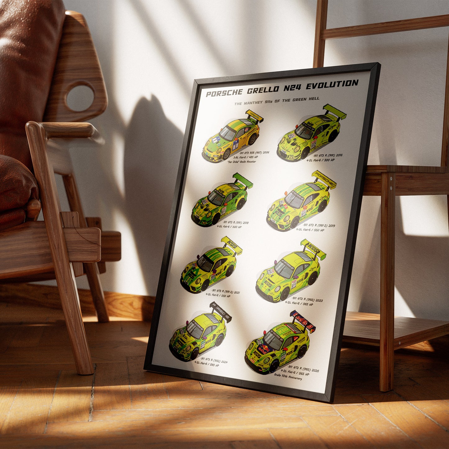 A framed poster leaning against a wall on a wooden floor, showing illustrated Porsche Grello N24 Evolution race cars in bright yellow-green and black. The poster is styled in a modern room with wooden chairs and warm sunlight casting shadows.