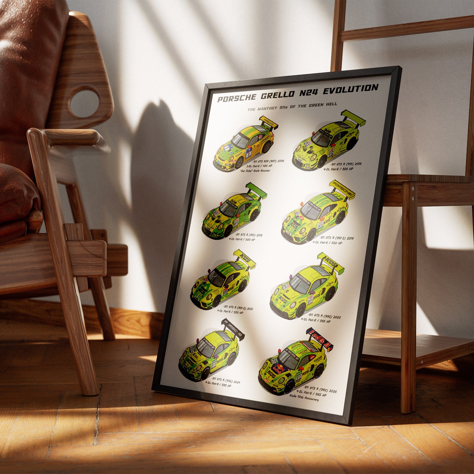 A framed poster leaning against a wall on a wooden floor, showing illustrated Porsche Grello N24 Evolution race cars in bright yellow-green and black. The poster is styled in a modern room with wooden chairs and warm sunlight casting shadows.